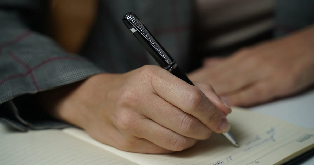 ペンでノートに書き込む手元