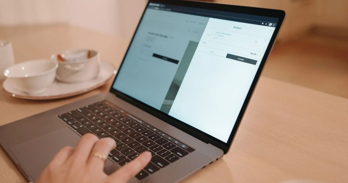 木のテーブルでノートパソコンを操作する人の手元